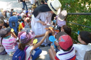 distribution de fleurs les enfants marquent les noms de leur famille devant la chapelle du precieux sang 11 juin 2022